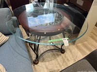 Angle view showing glass table top resting on metal base, with measurements visible on tape.