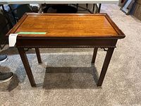 Front view of a small wooden hall table on a carpeted floor, showing the tabletops and legs in full.