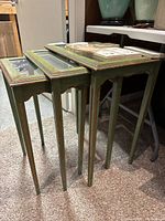 Photo of three wooden nesting tables stacked together, showing green distressed paint and glass inset tops.