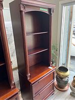 Full front view of large wooden office bookcase showing two office file drawers on the bottom and two open shelves on top.