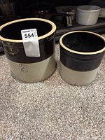 Two vintage stoneware crocks on carpet; one marked with '2'