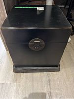 Closed black decorative wood box with latch seen from front.