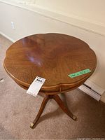 Top view of the wood side table showing scalloped edge and wood grain pattern with Masold auction tag and measurement tape