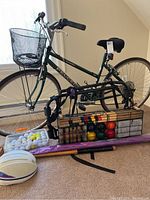 Full view of Peugeot women's step-through bicycle with front basket, bike rack, rugby ball, croquet set with balls and mallets, golf balls, and purple kite assembled in front of the bike.