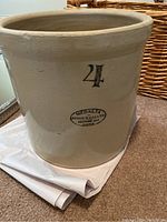 Medalta #4 stoneware pot showing label and number 4 on the surface, sitting on carpet with wicker basket behind