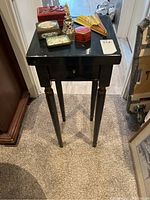 Full view of the tall black wooden table with Asian inspired decorative items on top.