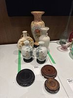 Overview of three porcelain vases, a pair of small Chinese export vases and three wood stands on table