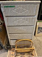 White wicker dresser front view with four woven drawers and green label showing measurements 28" x 17" x 51". Natural rattan magazine holder and small accent rug placed in front.