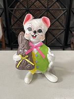 Photo of the white Annalee Easter bunny doll holding the chocolate bunny figure showing front details, clothing, and facial features.