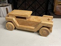 Side view of wooden car on a white surface showing general shape and condition.