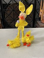 Photo of three yellow Annalee Easter collectible dolls including one bunny costume doll and two chick dolls