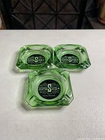 Three green glass ashtrays with Silver Spur logo visible on the bottom, showing front view and branding.