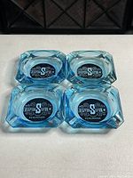 Top view of four blue glass ashtrays showing Silver Spur oval logo on top surface
