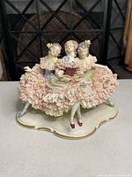 Front view of the porcelain figurine depicting three ladies in lace dresses singing, showing intricate lace details, pastel colors, and floral accents.
