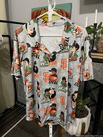 Front view of the button-up shirt showing character caricatures and team logos.