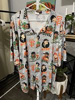 Front of the men's button-up shirt with player caricatures and Giants logos on grey fabric.