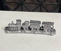 Front view of the handcrafted pewter train figurine showing the locomotive and three train cars on base.