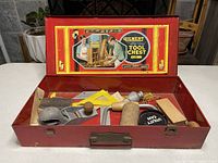 Open red metal Gilbert Big Boy tool chest showing label inside lid and assortment of hand tools inside chest.