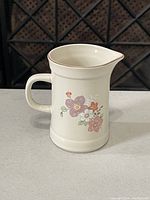 Front side view of the ceramic creamer jug showing floral design and handle