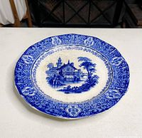 Full front view of the vintage Royal Warwick plate showing detailed blue pastoral design with ornate floral border on a white background.