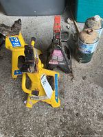 Photo showing three axle stands and two propane tanks on a concrete floor with light debris.