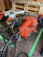 Photo showing two corded Black & Decker sanders on a workbench, dusty and worn.