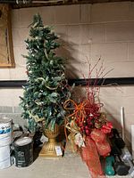 Artificial Christmas tree and decorative arrangement side by side, showing full view of tree and decor item