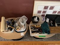 Wide photo showing two plastic containers filled with assorted crafting supplies including scissors, rotary cutter, wire spools, small scissors and packing materials.