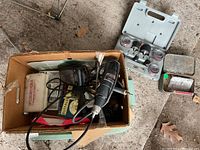 Overview of the cardboard box containing the Dremel rotary tool, power cords, and accessory case.