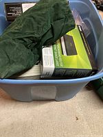 Large plastic bin containing various electronics covered partially with a green cloth