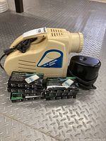 Wide view of 10X image enlarger, black electric pencil sharpener, and seven boxed pocket scales on floor.