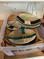 Set of uniquely designed plates with geometric patterns in various colors stacked in a box.