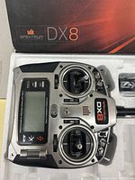 Spektrum DX8 remote control transmitter in foam packaging showing the front with joysticks, LCD screen, switches, and branding.