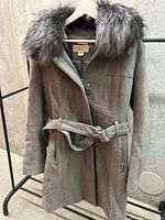 Front view of gray winter jacket featuring a detachable wide fur collar, button closure, and belted waist.