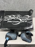 Black and gray protective wrist and palm pads displayed inside a black Rollerblade box with logo.