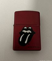 Front view showing red Zippo lighter with black and white Rolling Stones tongue and lips logo.