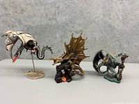 Full view of three dragon figurines displayed in a row on neutral background
