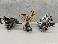 Three dragon figurines displayed side by side, showing overall design and color variations