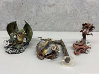 Three Seth MacFarlane dragon figurines in a single image displaying size and detail