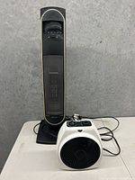 Both space heaters positioned side by side: small white heater in front and tall black Bionaire heater behind.