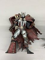 Spawn armored figure with red tattered cape and bone motifs, detailed sculpting and paintwork