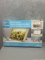 Photo of the Artist's Loft All Media Flat Surface Easel in original packaging showing the easel and an example sunflower painting on display, plus side views of the easel in use.