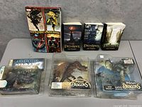 Photo shows collection of figures and books including Marvel Mystic Arcana box, three Lord of the Rings books, and three action figure boxes (two dragons and one spawn)