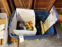 Blue bin containing tools with a white cardboard box of hand tools, yellow Canwood pneumatic nailer visible