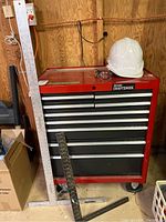 Front view of closed red rolling cabinet with measuring sticks and safety gear on top