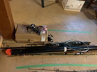 Overview photo showing fishing rods, reels, tackle box, and fishing tube arranged on floor