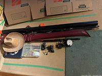 Overview of fishing rods, cowboy hat, tackle box, and books on the floor and carpet.