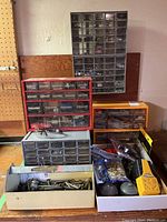 Full view of all tool accessory drawers stacked and placed on a wooden surface showing the variety of hardware and parts inside the compartments.