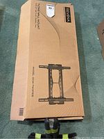 Closed cardboard box with product name, brand, model number, and illustration of wall mount on top surface.