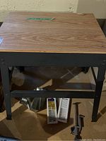 Full view of metal work bench with wood top, showing height and structure, with vent covers and a tool in foreground.